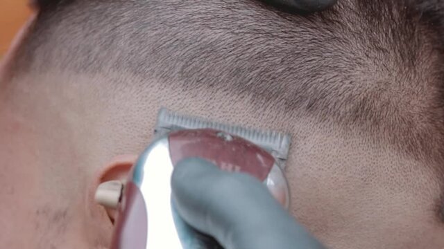 Barbero usando maquina de afeitar con modelo masculino en barbería 