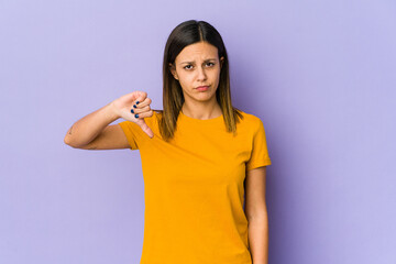 Young woman isolated on purple background showing a dislike gesture, thumbs down. Disagreement concept.