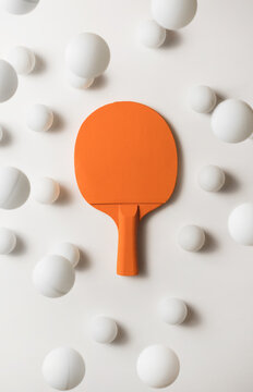Orange pIng pong racket and white balls flying