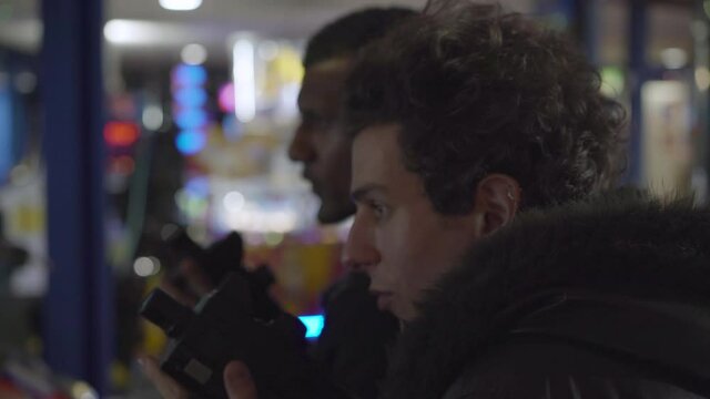 Two men playing with light guns in an indoor arcade