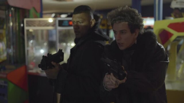Two men playing with light guns in an indoor arcade