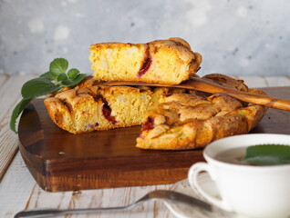 Apple summer seasonal charlotte pie with fresh apples and plums on a wooden kitchen board.Homemade cakes for tea.