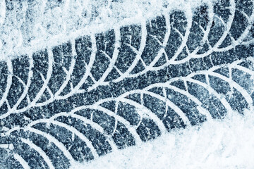 Snow tyre mark. Asphalt covered in snow. Dangerous road conditions. Car imprint on frozen ground. Tire trail on ice. © Paweł Michałowski