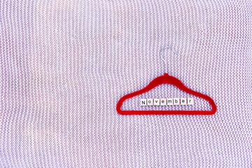 Clothes hanger on a knitted background with a composed word from the letters