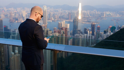 Fototapeta na wymiar Businessman standing on rooftop of skyscrapers in Hong Kong