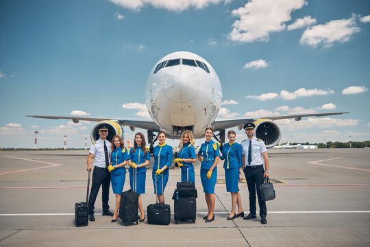 Airline workers with travel suitcases standing outdoors in airfield