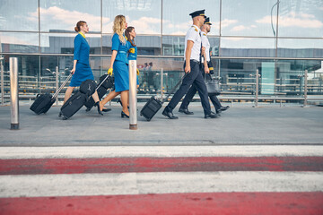Airline workers carrying travel suitcases at airport