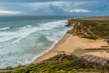 Seascape of Ribeira d'Ilhas beach, its wooden walkways and trails on the hill, Ericeira PORTUGAL