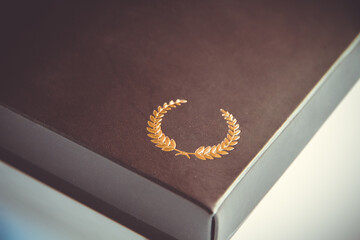 Black gift box detail with a golden laurel wreath icon