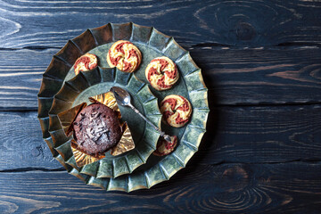 
There is a cheesecake in a vintage plate. It is surrounded by strawberries and saffron leaves. Black background with space for text. Top view.