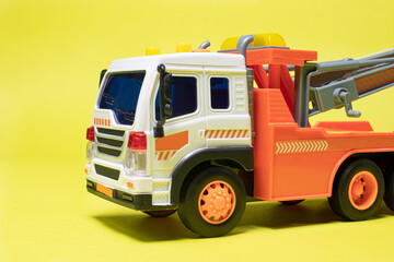 Toy orange tow truck on yellow background. Children's car for loading and transporting cars.