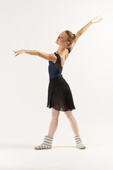 woman ballerina in pointe shoes and in a tutu dances on a light background in full growth 