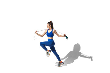 Fototapeta na wymiar Movement. Beautiful young female athlete practicing on white studio background, portrait with shadows. Sportive fit model in motion and action. Body building, healthy lifestyle, style concept.