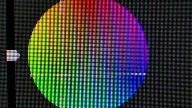 Color correction circle wheel on the monitor screen close up. Pixels zoomed in with red, blue, and green glowing crystals and patterns on a computer graphics monitor.