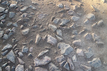 stones on the ground near the road lit by the sun