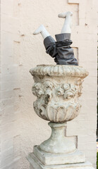 Obraz na płótnie Canvas Childs legs upside down inside a large stone garden urn