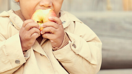 little child eats an apple. concept of the coming of the autumn season. Children's fashion