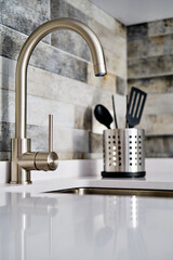 Faucet and sink on tiled wall background in modern domestic kitchen