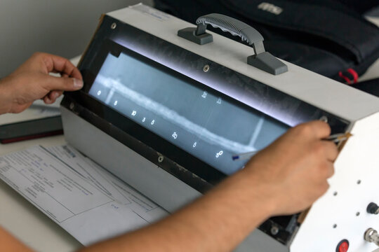 The radiography film operator level 2 (ndt) evaluation radiographs of the welds with viewer and he is writing some reports. The weld metal has some defects.