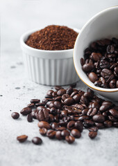 Two bowls with fresh raw coffee beans and powder on light background.