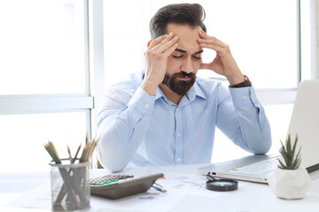 Young man working on computer and having headache