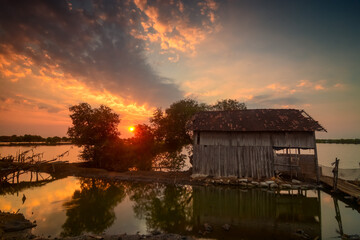Fototapeta na wymiar Sunset reflection on the lakes. Old bamboo house. Fisherman's house. 