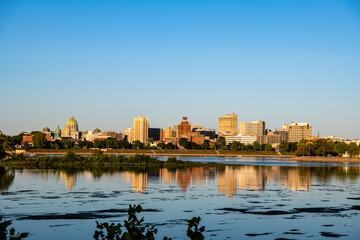 A photo of Riverfront Park seen from across the Susquehanna River at sunset. The buildings reflections are shown in the river. 