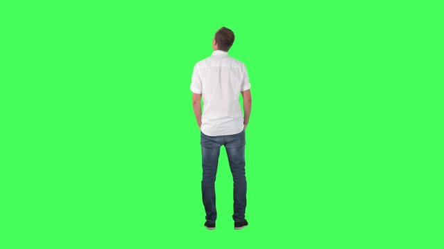 Back view of amazed interested young man watching shop window or gallery copy space. Full body on green screen chroma key background.