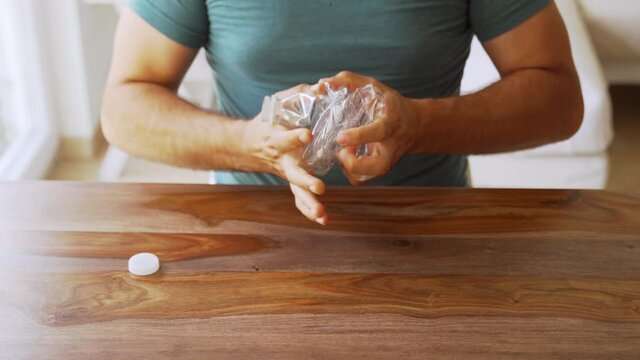 The man crushes the empty water bottle to prepare it for recycling.