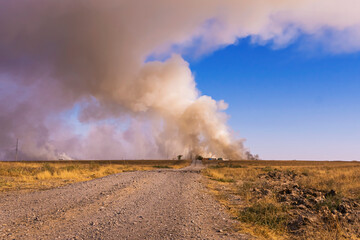 Fire in the steppe. Fire at an industrial plant. Ecological problem. Steppe road. Environmental pollution. Environmental disaster. Garbage in the steppe. Smoke screen over the plain. Dry yellow grass.