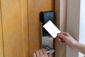 Door access control - woman hand holding white mockup key card to lock and unlock door. digital...