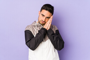 Fototapeta premium Young caucasian man isolated on purple background yawning showing a tired gesture covering mouth with hand.