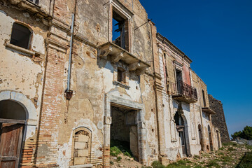 Fototapeta premium Craco, Matera, Basilicata, Italy. Ghost town destroyed and abandoned following a landslide. Collapsed houses and the remains invaded by vegetation. Broken walls, windows and doors, crumbling balconies