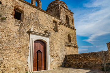 Fototapeta na wymiar Craco, Matera, Basilicata, Italy. The ghost town destroyed and abandoned following a landslide. The ancient church of the city, with its bell tower, almost completely destroyed. The large wooden door.