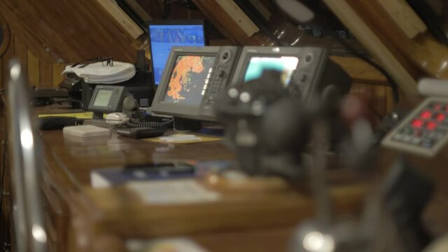 A light is switched on to show the captain's bridge where screens, monitors, levers and sailing devices are used to sail.