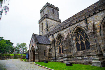 Fototapeta na wymiar Fachada lateral de entrada de iglesia gótica con césped y adoquines
