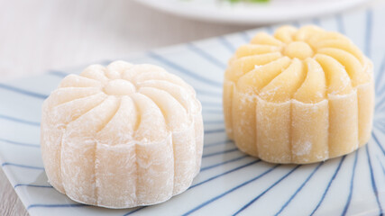 Colorful snow skin moon cake, sweet snowy mooncake, traditional savory dessert for Mid-Autumn Festival on bright wooden background, close up, lifestyle.