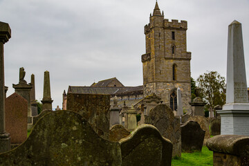 Fototapeta na wymiar Vista de cementerio desde lapidas y torre de iglesia gótica