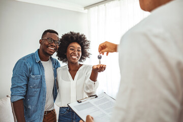 Real estate agent giving keys to couple of customers. Happy young couple getting keys of their new...