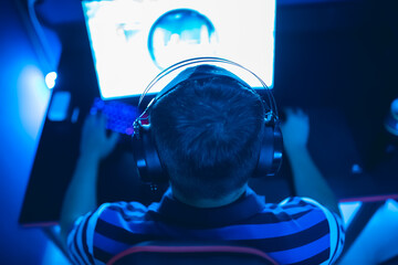 Professional gamer playing online games tournaments pc computer with headphones, Blurred red and...