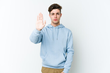 Young caucasian man isolated on white background standing with outstretched hand showing stop sign, preventing you.