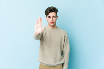 Young caucasian man isolated on blue background standing with outstretched hand showing stop sign, preventing you.