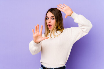 Fototapeta premium Young caucasian woman isolated on purple background being shocked due to an imminent danger