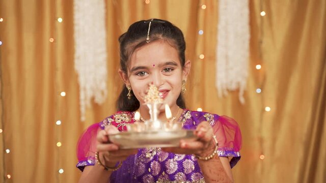 POV shot of cute little girl in traditional dress doing aarti or offering light to god during Hindu Religious festival ceremony