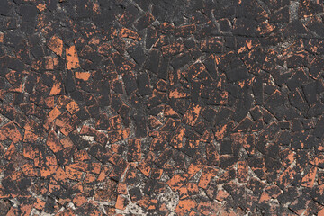 An old black-red mosaic wall made of fragments of bricks.