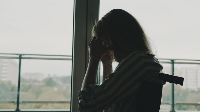 depressed young disabled woman near the window having a headache. High quality 4k footage