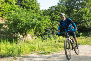 Obraz premium A sportsman who rides a mountain bike on a forest trail, wearing a face mask against air pollution and covid19 coronavirus. Cyclist wearing a protective mask.