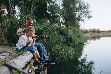 boy fishing with his grandfather outdoors at the lake