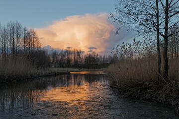 red cloud cloud over the forest by the lake at sunset