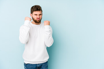 Fototapeta premium Young caucasian man isolated on blue background upset screaming with tense hands.